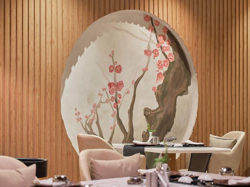 Interior de restaurante con paredes de madera, sillas cómodas y decoración floral oriental.