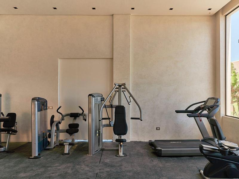 Gimnasio moderno con equipos de entrenamiento y ventana grande con vistas a árboles.