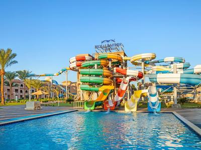 Parque acuático con varios toboganes de colores junto a una piscina bajo un cielo azul.
