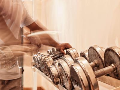 Persoon tilt halters op in een helder fitnesscentrum.