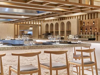 Elegantní dřevěný bar se stoličkami a regály, útulná a moderní atmosféra.