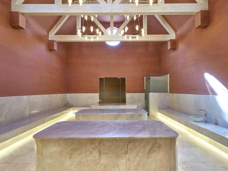 Moderní interiér s červenými zdmi, mramorovými stoly a závěsnými lampami.