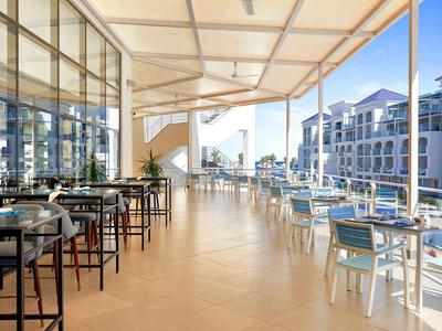 Terraza luminosa con mesas y sillas con vista a edificios modernos a la luz del día.