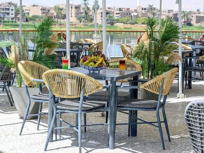 Terraza con sillas y mesas con vista al agua y la ciudad al fondo.