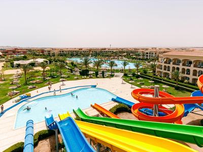 Colorful water slides lead to a pool in a resort with green gardens and buildings in the background.