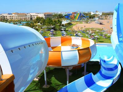 Colorful water slides in a water park with green grass and buildings in the background.