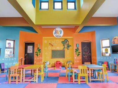 Sala giochi colorata con tavoli, sedie e decorazioni murali vivaci.