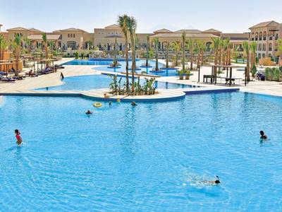 Ampia piscina all'aperto in un resort con palme e lettini.