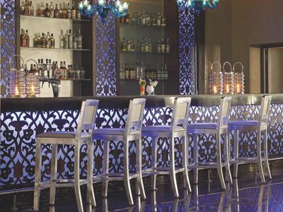 Bar elegante con sgabelli bianchi e illuminazione ambientale viola e blu.