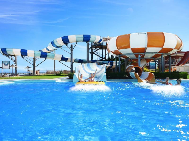 Grande scivolo d'acqua con discese colorate in una piscina sotto un cielo azzurro.