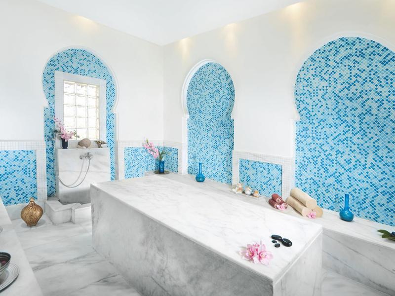 Interno di hammam con marmo bianco e piastrelle blu decorative.