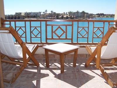 Pohodlný hotelový pokoj s obloukovým oknem, postelí, židlemi a měkkým přirozeným světlem.