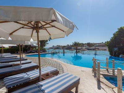Zone de piscine avec chaises longues et parasols par une journée ensoleillée.