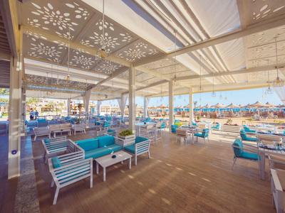 Bar de playa luminosa con áreas de asientos modernas y vista al mar bajo toldo solar.