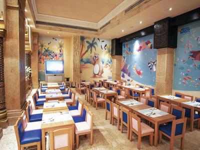 Comedor luminoso con mesas de madera, sillas azules y murales temáticos marinos.