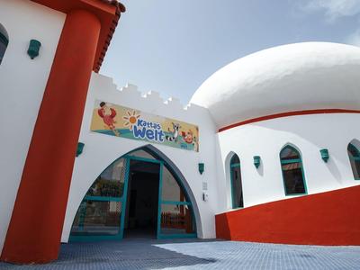 Hotel moderno con formas redondeadas blancas y rojas bajo cielo azul.