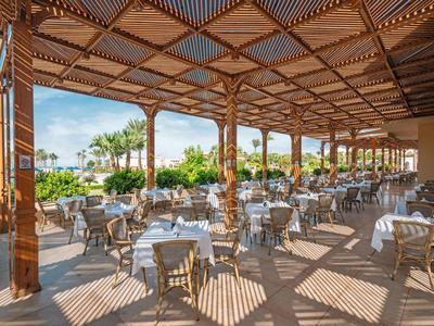 Terrasse de restaurant couverte avec poutres en bois et tables avec nappes blanches.