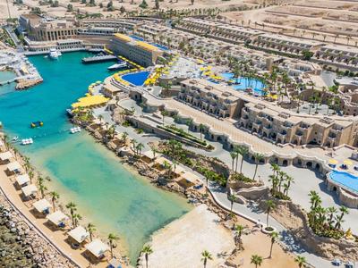 Aerial view of a luxury resort with pool, lagoon, and sandy beach in the desert.