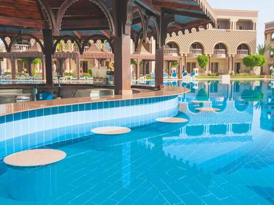 Piscina con bar y asientos bajo el agua en un resort con palmeras.