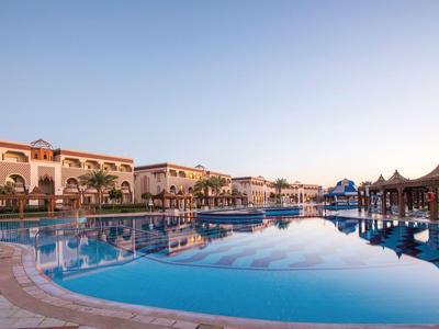 Gran piscina del hotel con tumbonas blancas y palmeras bajo un cielo despejado