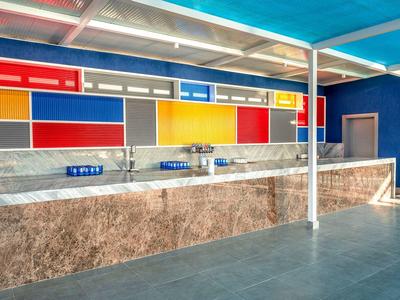 Moderne, farbige Bar mit Marmor-Theke und hellem Dach, teilweise mit blau, rot, gelb und grauen Flächen.