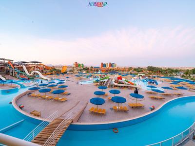 Waterpark met glijbanen, blauwe parasols en ligstoelen in een zonnige omgeving.