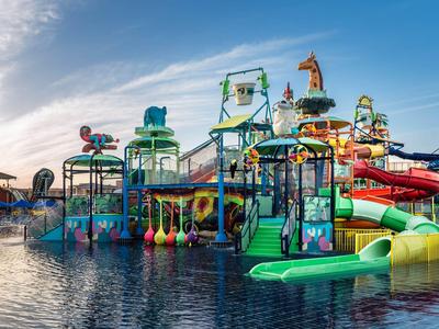Kleurrijk waterpark met glijbanen en speelzones bij zonsondergang.