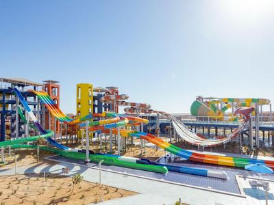 Kleurrijk waterpark met meerdere glijbanen en zwemgebieden op een zonnig strand.