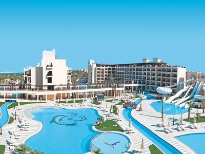 Großer Hotelkomplex mit mehreren Pools und Wasserrutschen unter klarem blauem Himmel.