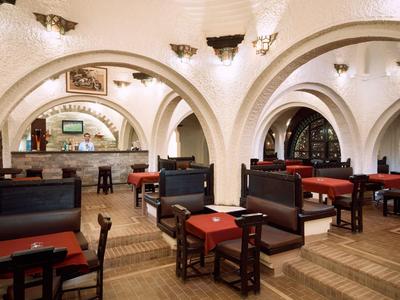 Traditionelles Restaurant mit gewölbten Decken, Holzmöbeln und rot gedeckten Tischen.