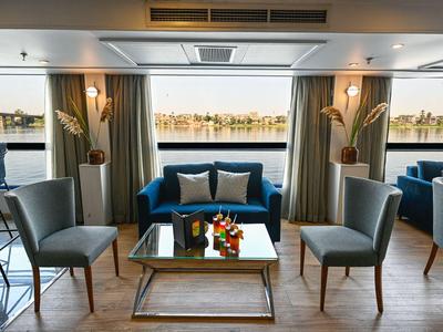Moderne woonkamer met bank, stoelen en uitzicht op het water.