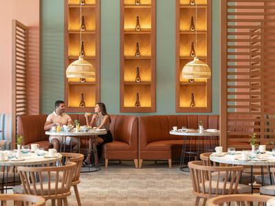 Gemütliches Restaurant mit braunen Ledersitzbänken, Holzstühlen und dekorativer Wandbeleuchtung.