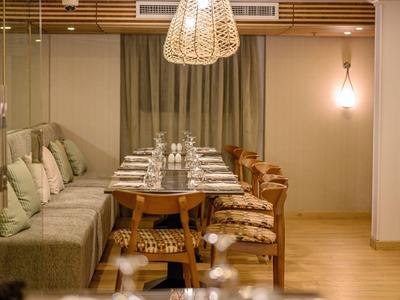 Coin repas confortable avec tables en bois, chaises et éclairage doux.
