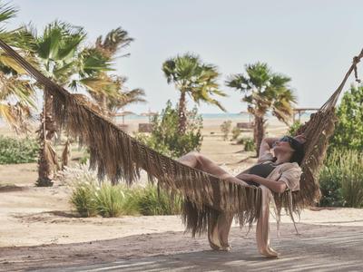 Une femme se détend dans un hamac dans un jardin tropical d'hôtel.