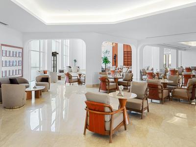 Heller, moderner Hotel-Loungebereich mit bequemen Sesseln und einem spiegelnden Boden.