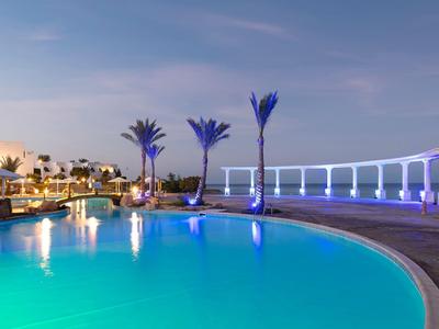 Velký bazén s osvětlenými palmami a moderní architekturou při soumraku v hotelu