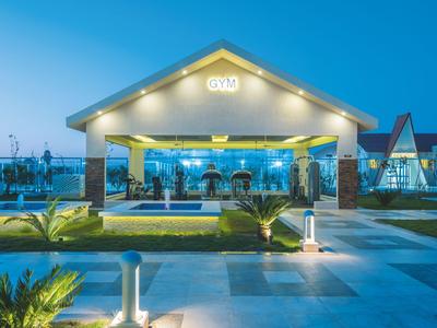 Illuminated modern hotel entrance at dusk with plants and seating areas.