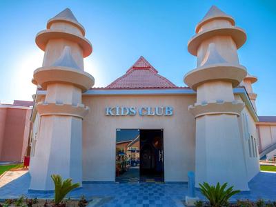 Entrée d'un club enfants avec architecture de château et tour en beige.