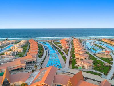 Aerial view of a coastal resort with row houses, canals, and a view of the sea.