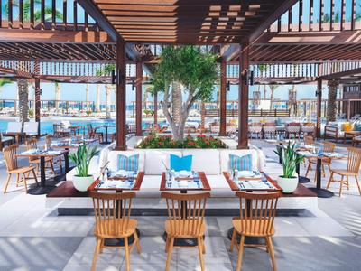 Área exterior abierta y moderna con asientos, muebles de madera y vista al mar.