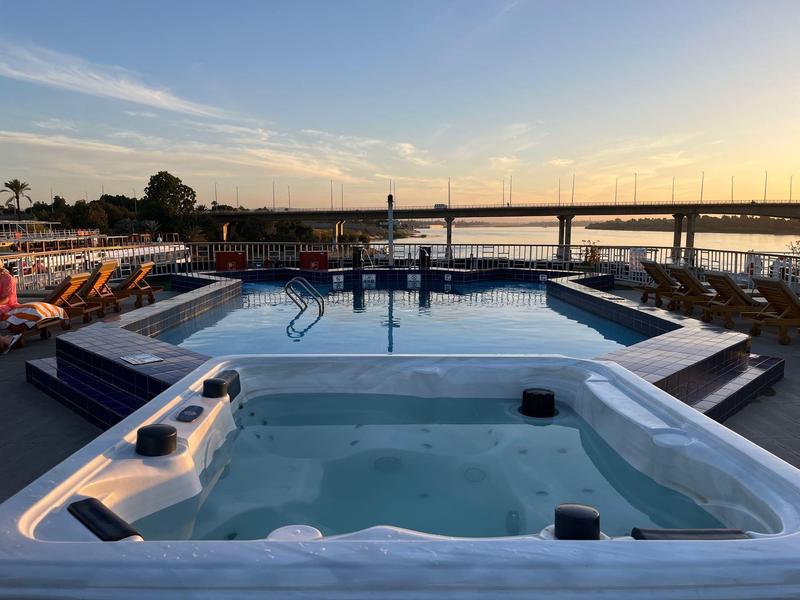 Área moderna de jacuzzi y piscina con vista a un puente al atardecer.