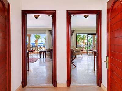 View through two doorways revealing a bright dining area with large windows and palm trees outside.