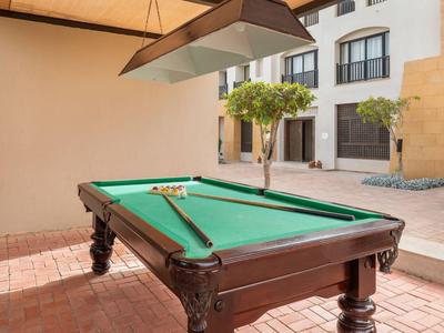 Stół bilardowy z zielonym suknem w zacienionym dziedzińcu hotelu.