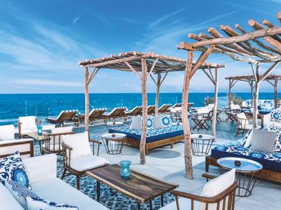 Terrazza aperta con mobili in legno e vista sul mare in una giornata di sole.