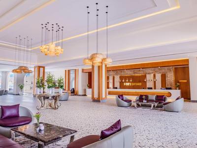 Eleganckie lobby hotelowe z nowoczesnymi meblami, żyrandolami i ciepłymi drewnianymi akcentami.