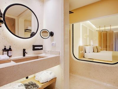 Moderne hotelbadkamer met ronde spiegels, beige tinten en voorzieningen op de wastafel.