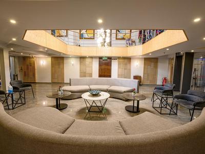 Modern hotel lounge with gray sofas, tables, and soft lighting in the atrium.
