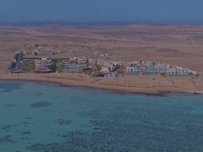 Petit village côtier entouré de désert et d'eau de mer bleu clair.