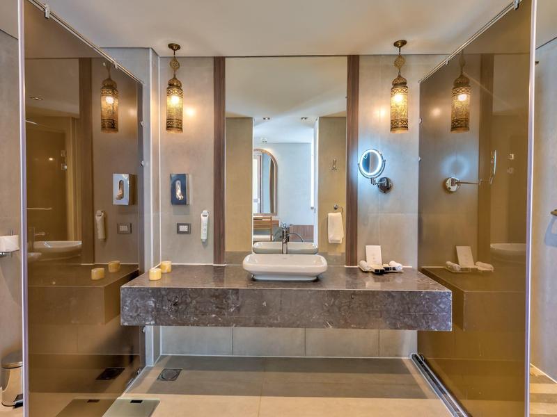 Salle de bain d'hôtel moderne avec doubles lavabos, miroirs ronds et douches en verre.