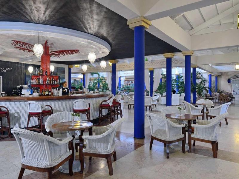 Elegantní otevřený bar s pohodlným posezením a bílými trámy na stropě.